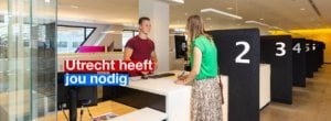 Iemand wordt geholpen door een medewerker bij een service balie. In beeld staat de tekst Utrecht heeft jou nodig.